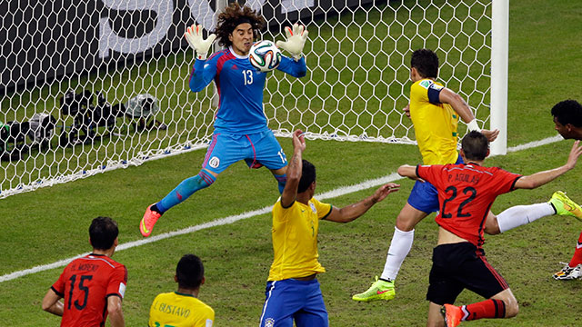Mexico's goalkeeper Guillermo Ochoa, left, saves a header by Brazil's Thiago Silva during the group A World Cup soccer match between Brazil and Mexico. Themba Hadebe/AP